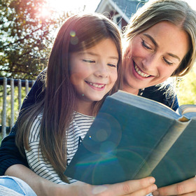 Mutter und Tochter lesen Buch in Garten
