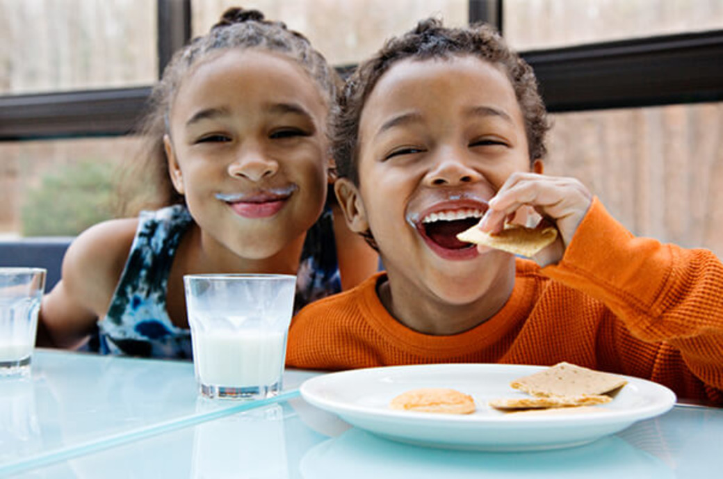 Geschwister essen Cracker und trinken Milch