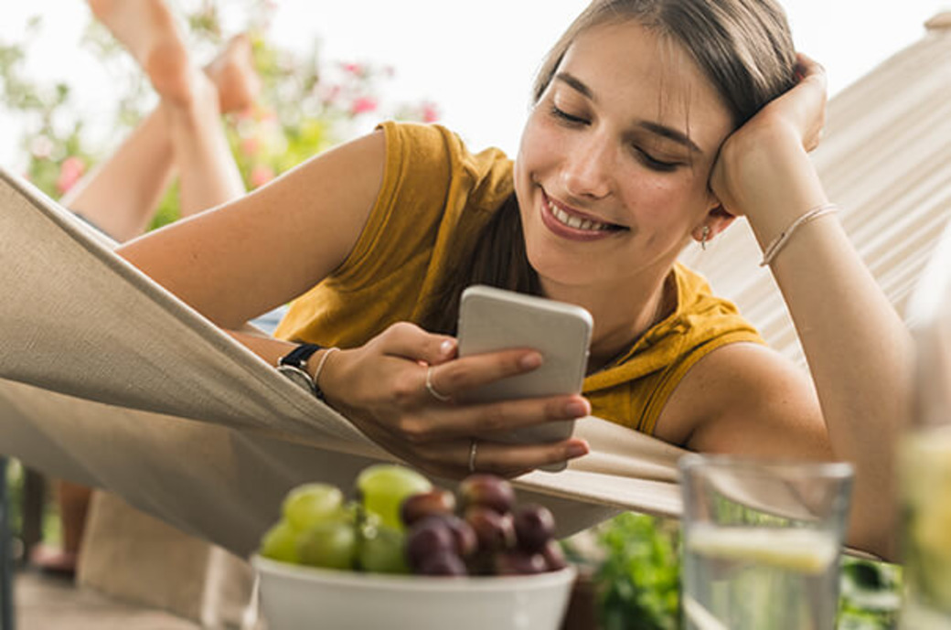 Junge Frau mit Handy in Hängematte