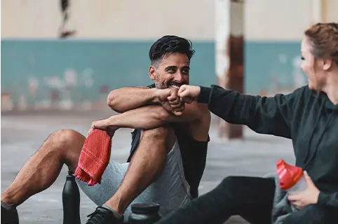 Zwei sportliche Personen sitzen auf dem Boden