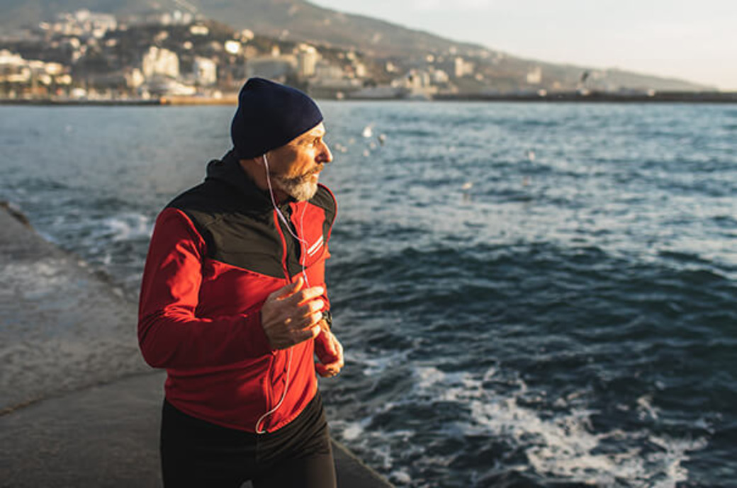 Älterer Mann joggt am Meer