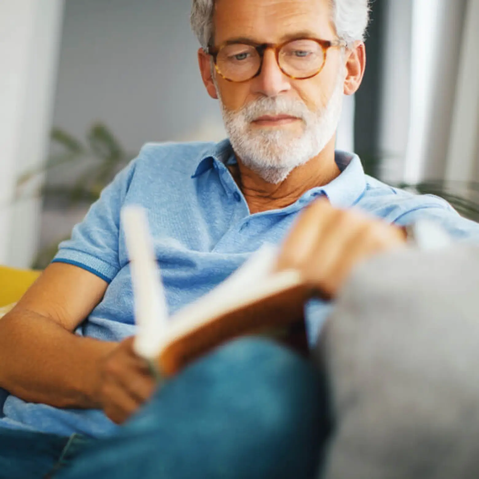 Älterer Herr liest ein Buch auf der Couch