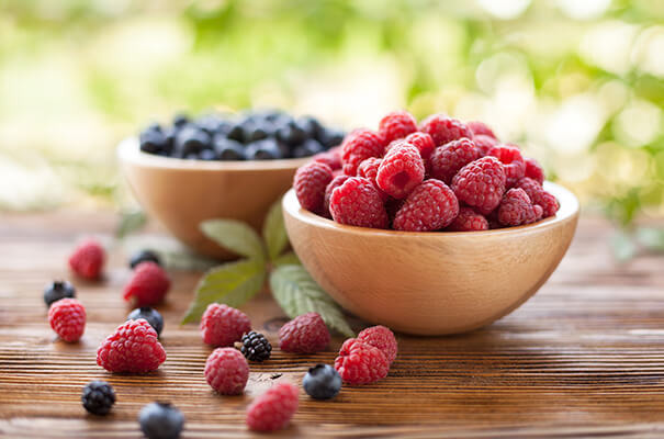 Holzschalen mit Himbeeren und Heidelbeeren