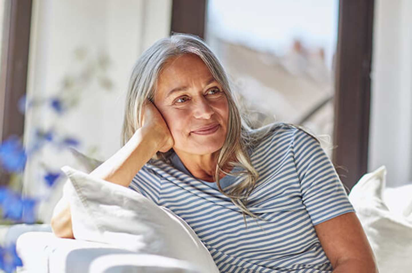 Frau mit grauen Haaren sitzt auf Sofa
