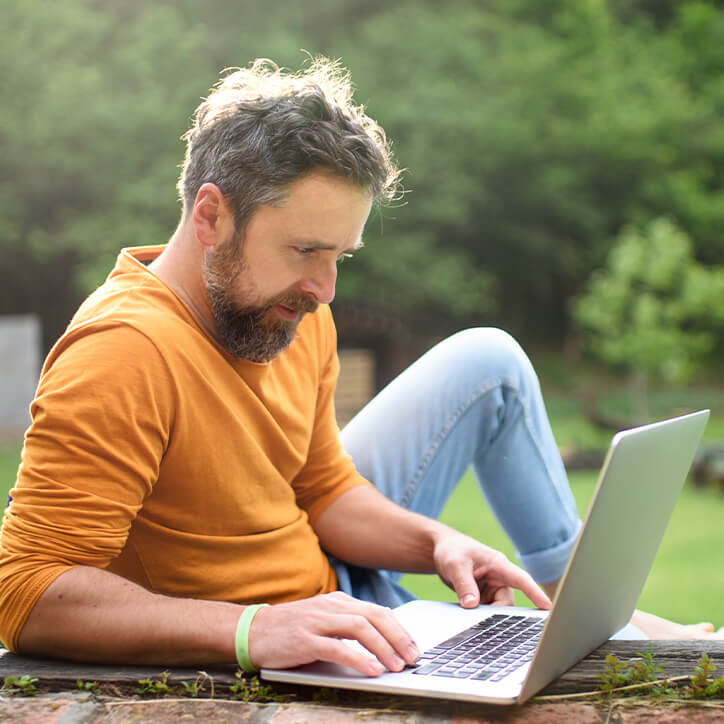 Mann mit Laptop im Garten