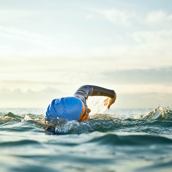 Frau schwimmt im Meer, um Gelenkschmerzen beim Sport zu vermeiden.