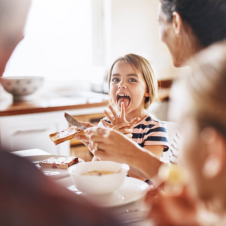 Mädchen beim ausgewogenen Frühstück mit ihrer Familie, um ihre Abwehrkräfte zu stärken.