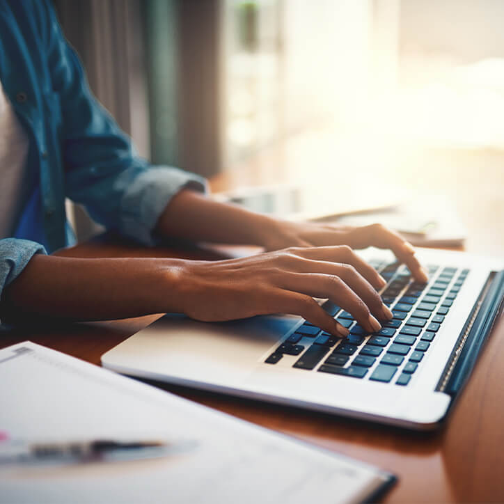 Frau erkundigt sich am Laptop über eine erhöhte Basaltemperatur und weiteren Schwangerschaftsanzeichen.